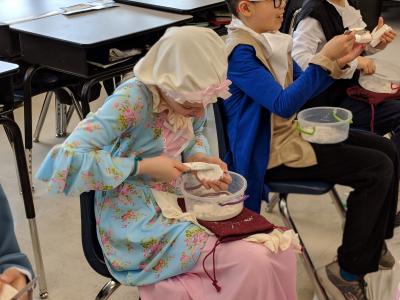 student wearing colonial outfit while making soap